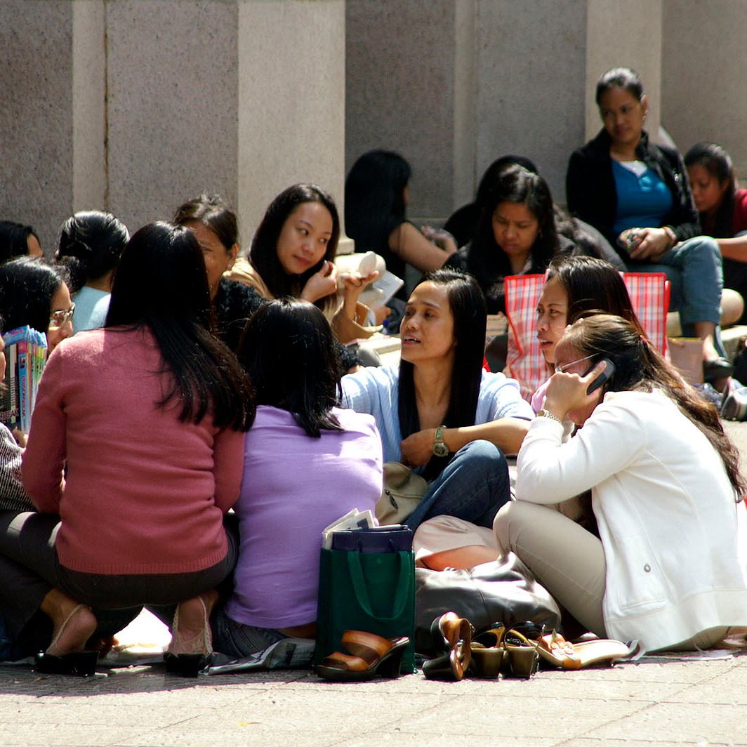 Filipina maids sitting in a circle outdoors