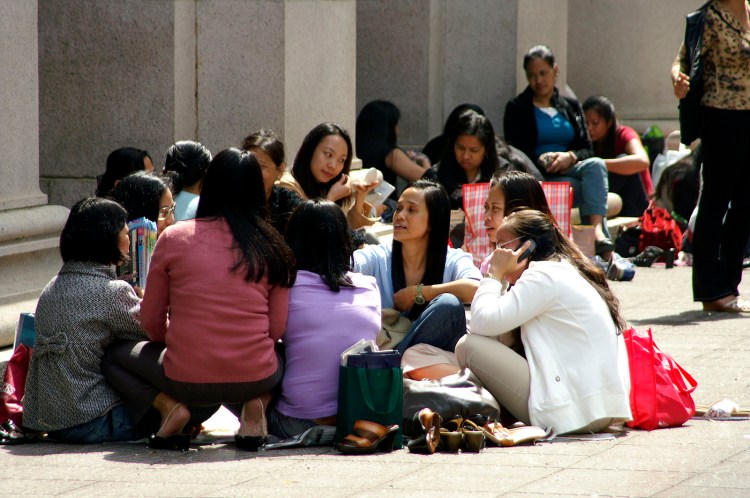 Filipina maids sitting in a circle outdoors