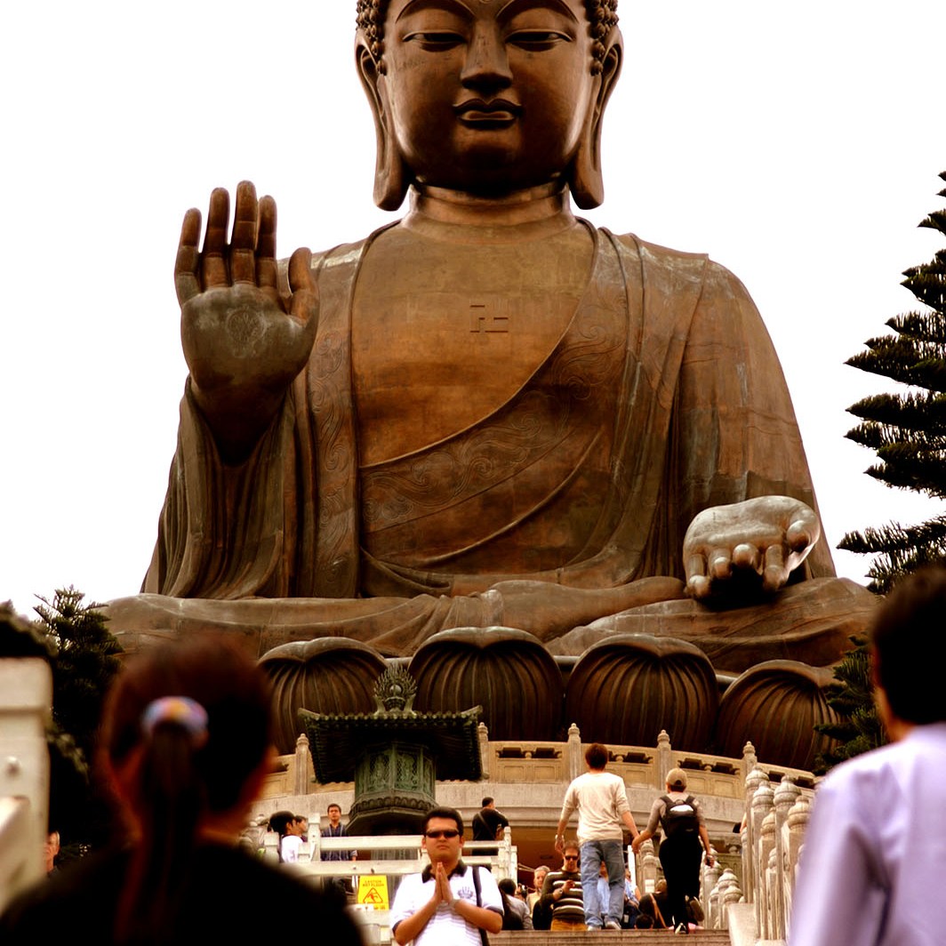Man poses for a picture in reverence at the top of the Big Buddha