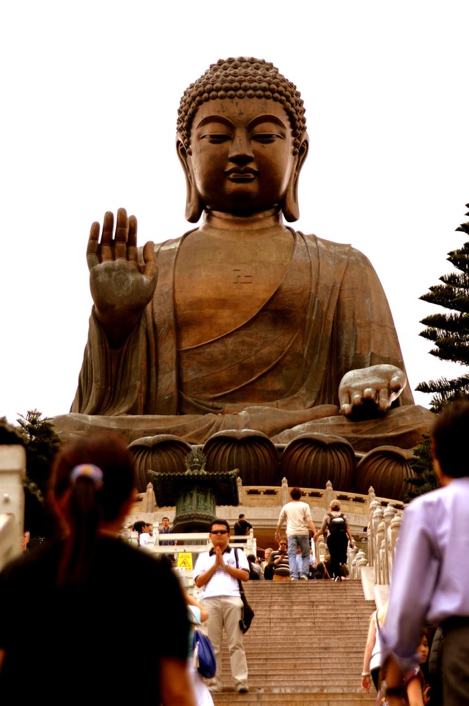 Man poses for a picture in reverence at the top of the Big Buddha