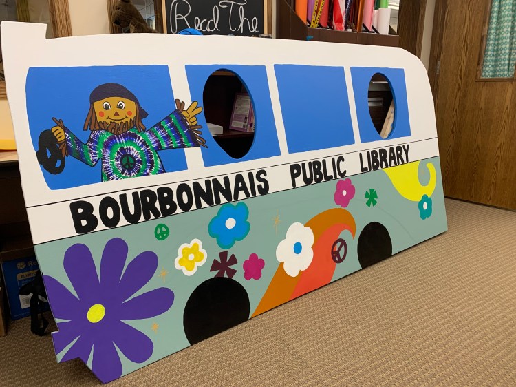 Large wooden bus with cutouts for children to stick their heads in for pictures. Painted to look like a VW with a groovy scarecrow driving.